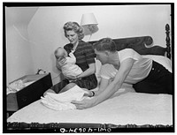 Washington, D.C. In the evening, Hugh Massman and his wife fold diapers. Joey's bureau drawer crib is moved to the side of their bed for the night. Sourced from the Library of Congress.