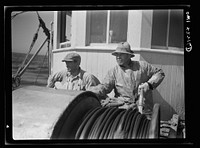 On board a fishing vessel out from Gloucester, Massachusetts. Winch control men intent on seeing to it that the proper amount of cable is let out at the proper spot. Sourced from the Library of Congress.