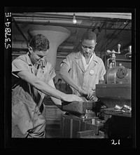 NYA (National Youth Administration) work center, Brooklyn, New York. Two men, white and , who are receiving training in machine shop practice, shown setting up shaper work to cut forty-five degree angles at base for surface gauge. Sourced from the Library of Congress.