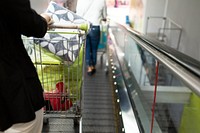Woman standing on escalator with shopping cart