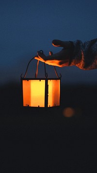 Phone wallpaper background, hand holding a lantern in the dark