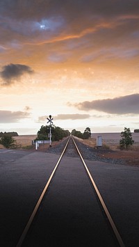 Aesthetic iPhone wallpaper background, railroad in the countryside under a golden sky