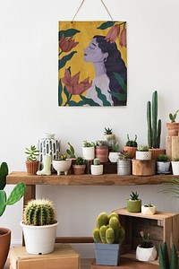 Painting hanging over a shelf full of cacti and succulents