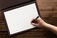 White paper on a folder with hand holding a pen