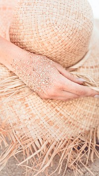 Mobile phone wallpaper, beach sandy hand touch a straw hat warm tone filter