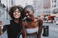 Smiling women video calling friends in the city