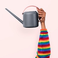 Watering can gardening tool held by a person with rainbow sleeves