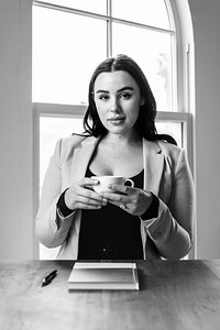 Businesswoman drinking coffee in a meeting room, black and white photo