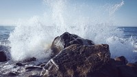 A wave splashing into a coastal rock, causing spray. Original public domain image from Wikimedia Commons