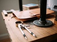 A workbench with a compass, binder, and tools on top. Original public domain image from <a href="https://commons.wikimedia.org/wiki/File:Workbench_and_tools_(Unsplash).jpg" target="_blank" rel="noopener noreferrer nofollow">Wikimedia Commons</a>
