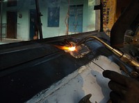 A person welding metal in a workshop. Original public domain image from Wikimedia Commons