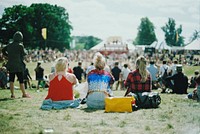 Young women sitting at the back of an audience at a music festival. Original public domain image from Wikimedia Commons