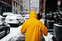 A person with a yellow cape is walking on a snowy sidewalk in New York. Original public domain image from Wikimedia Commons