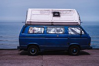 Blue van with window protectors and a container on the roof. Original public domain image from Wikimedia Commons