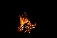 A blazing fire in a firepit in the dark at a campsite. Original public domain image from Wikimedia Commons