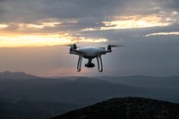An aerial shot of a drone in flight over hilly terrain in Greece during a cloud covered sunrise-or-sunset. Original public domain image from <a href="https://commons.wikimedia.org/wiki/File:Drone_flying_over_hills_(Unsplash).jpg" target="_blank" rel="noopener noreferrer nofollow">Wikimedia Commons</a>