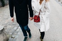 A fashionable couple holding hands while walking on the street. Original public domain image from Wikimedia Commons