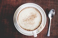 A frothy cup of coffee with cinnamon sprinkled on top of it in a white mug. Original public domain image from Wikimedia Commons