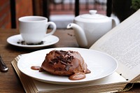 Chocolate dessert on an open book with a tea pot and tea cup in the background. Original public domain image from <a href="https://commons.wikimedia.org/wiki/File:Profiterole_(Unsplash).jpg" target="_blank" rel="noopener noreferrer nofollow">Wikimedia Commons</a>