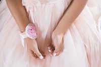 Close up of the hands of a little girl in a dress with a pink wrist corsage. Original public domain image from Wikimedia Commons