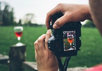 Close-up of a photographer taking a photo of a glass of wine with a camera.. Original public domain image from <a href="https://commons.wikimedia.org/wiki/File:Wine_through_viewfinder_(Unsplash).jpg" target="_blank" rel="noopener noreferrer nofollow">Wikimedia Commons</a>