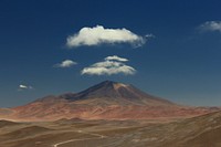 Fluffy clouds over a tall mountain with red rock slopes in Salar de Incahuasi. Original public domain image from <a href="https://commons.wikimedia.org/wiki/File:The_Lonely_Mountain_(Unsplash).jpg" target="_blank" rel="noopener noreferrer nofollow">Wikimedia Commons</a>