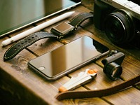 An iPhone, an Apple Watch and a digital camera on a wooden surface. Original public domain image from Wikimedia Commons