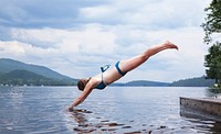 Woman in a swimsuit dives off a lake pier into the water. Original public domain image from Wikimedia Commons