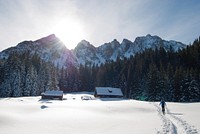 A person walking in the snow to a house near sunny the mountain peaks. Original public domain image from <a href="https://commons.wikimedia.org/wiki/File:A_sunny_snow_capped_mountain_over_a_house_(Unsplash).jpg" target="_blank" rel="noopener noreferrer nofollow">Wikimedia Commons</a>