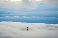 Golden Gate Bridge peeks through clouds on a foggy, blue morning. Original public domain image from Wikimedia Commons