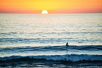 Surfer in the ocean waves, orange sunset. Original public domain image from Wikimedia Commons