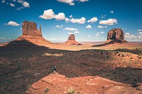 Hiker stands atop a peak of a rock formation in the desert of Oljato-Monument Valley. Original public domain image from Wikimedia Commons