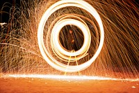 Bright light spark circle twirl photo at nighttime in Monson. Original public domain image from <a href="https://commons.wikimedia.org/wiki/File:Orange_light_sparks_(Unsplash).jpg" target="_blank" rel="noopener noreferrer nofollow">Wikimedia Commons</a>