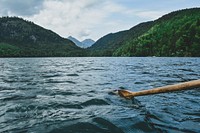 A boat view of a wooden oar in water on a choppy lake in the mountains. Original public domain image from Wikimedia Commons