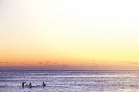 3 people in the calm, shallow sea at Sydney Beach, beneath a beautiful orange and purple sunset sky. Original public domain image from <a href="https://commons.wikimedia.org/wiki/File:Sydney_sunset_sea_paddling_(Unsplash).jpg" target="_blank" rel="noopener noreferrer nofollow">Wikimedia Commons</a>