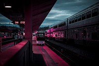 Pink light glows on an urban train station as train cars pass. Original public domain image from Wikimedia Commons