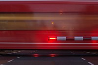 Red train at level crossing, red and white barrier, motion blur • public domain. Original public domain image from Wikimedia Commons