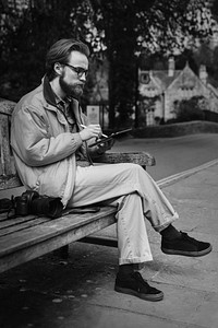 Man sitting on a bench and working on tablet in the village