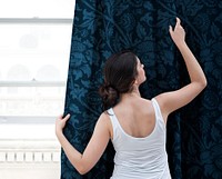 Woman closing window curtain in the living room