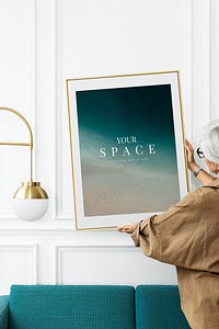 Senior woman hanging a picture frame in a luxury living room