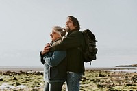 Senior tourist couple hugging at the beach