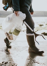 Beach cleanup volunteer carrying garbage bag for environment campaign