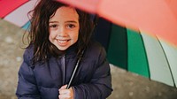 Little girl smiling with an umbrella while on a family trip outdoors portrait