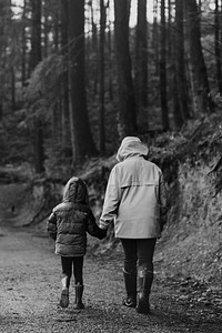 Mother walking with her daughter in the forest rear view black and white