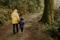 Mother walking with her daughter in the forest rear view