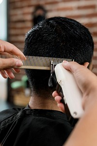 Hairdresser trimming hair of the customer at a barbershop 
