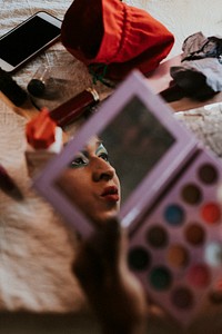 Man in drag applying eyeshadow, entertainment makeup look