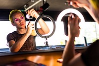 Non-binary person applying eye makeup, using LED ring light, beauty blogger