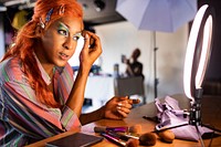 Drag queen in ginger wig putting on makeup