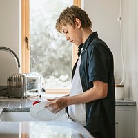 Boy washing dishes, household chores for kids